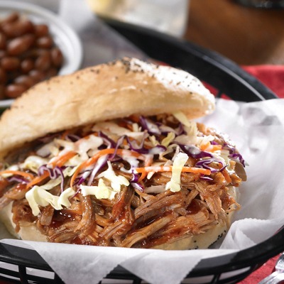 Carolina shredded pork and coleslaw sandwich in a basket with baked means