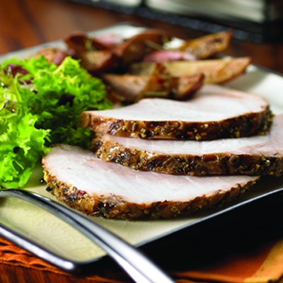Herb crusted pork roast slices on a plate with lettuce and potatoes