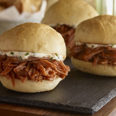 Three pot roast sliders on a tray with garlic aioli