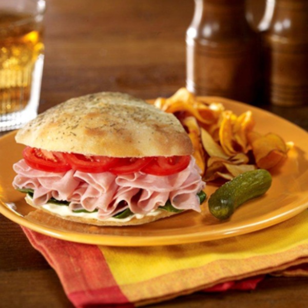 Ham dinger sandwich on a plate with pickles and potato chips