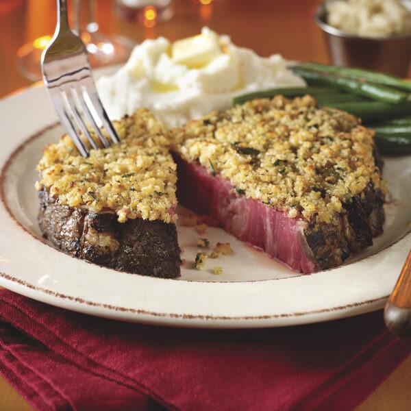 Horseradish crusted prime rib on a plate with mashed potatoes and green beans