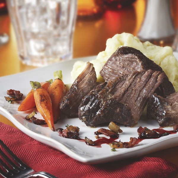 Braised pot roast with bacon onion relish, carrots, and mashed potatoes on a plate